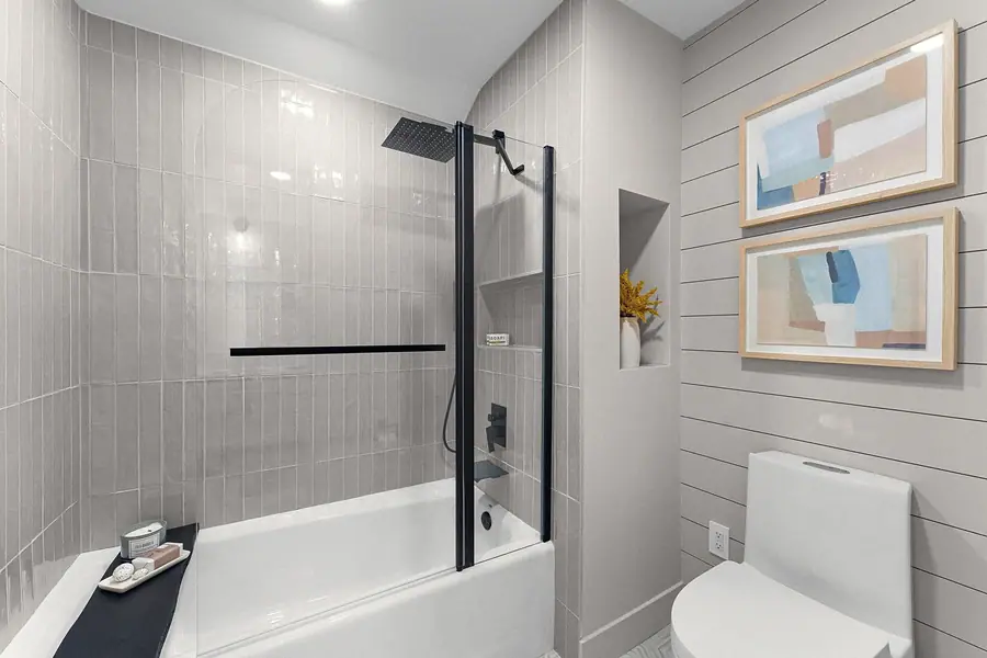 Grand Vista bath with glass tub-shower, gray tile, and shiplap wall art