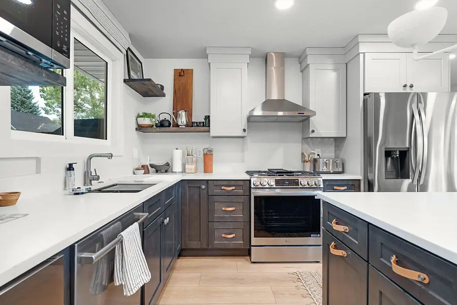 Midway kitchen with dark lower cabinets, white counters, stainless range, and open shelves