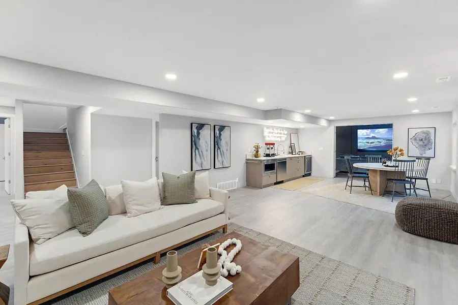 Grand Vista lower-level living room with cream sofa, wood coffee table, and open kitchen beyond