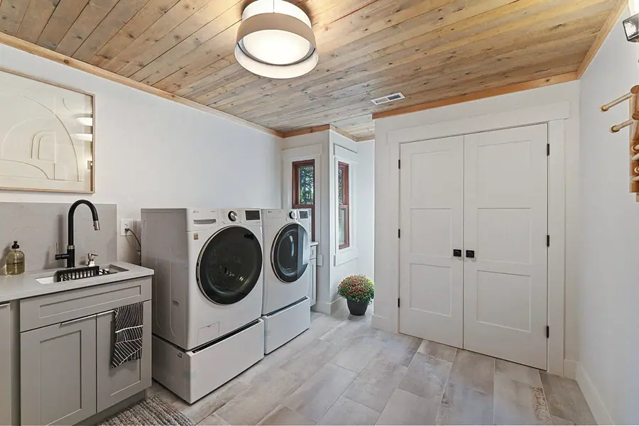 Matterhorn Hygge House laundry room with wood ceiling, washer dryer, and double closet doors