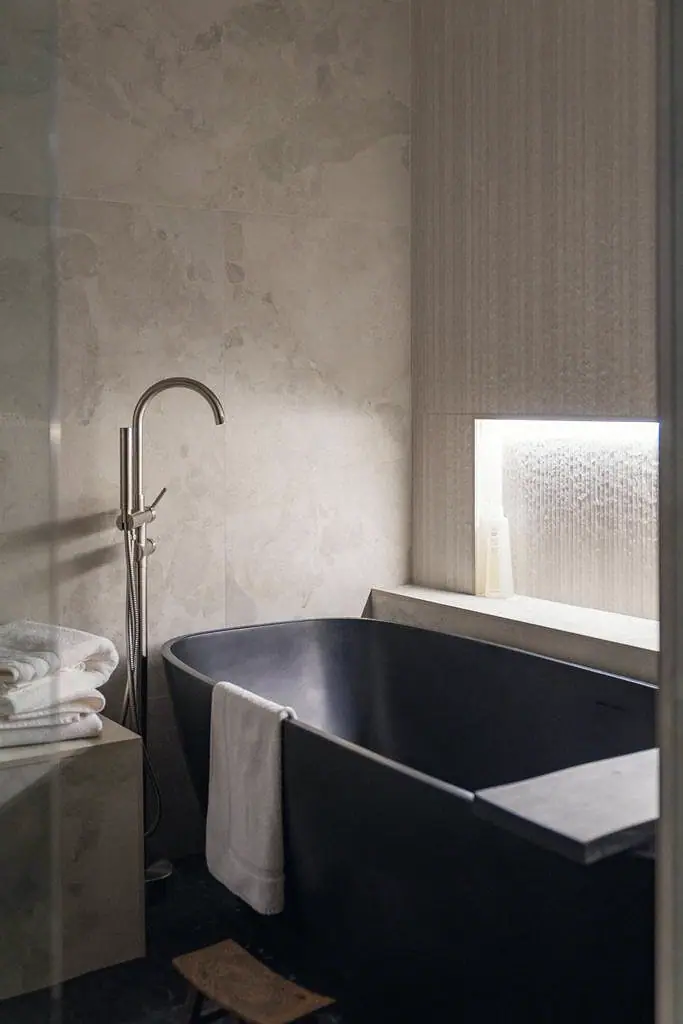 Crista da Montanha spa bath with freestanding black soaking tub, marble walls, and floor-mounted faucet