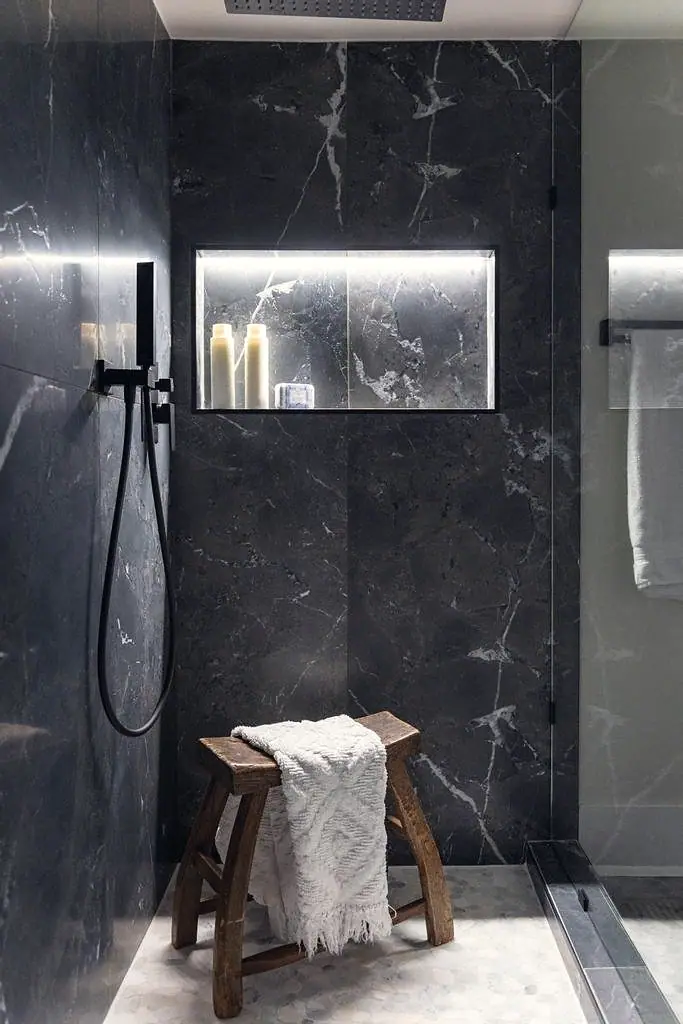 Crista da Montanha dark marble shower niche with black fixtures and wood stool