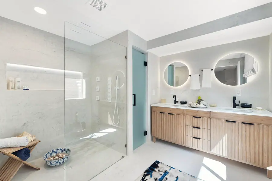 Elysium spa bath with marble shower, fluted wood vanity, and dual lit mirrors