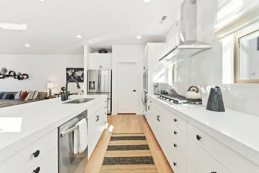 Silver Creek kitchen galley with white counters, black fixtures, and living room beyond