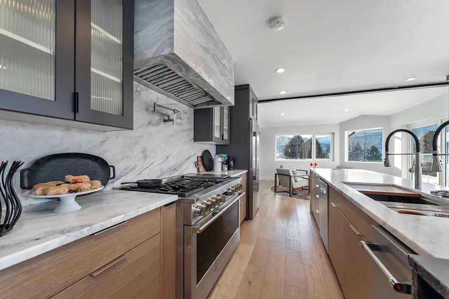 Kitchen cooking wall with marble hood, range, and island beyond