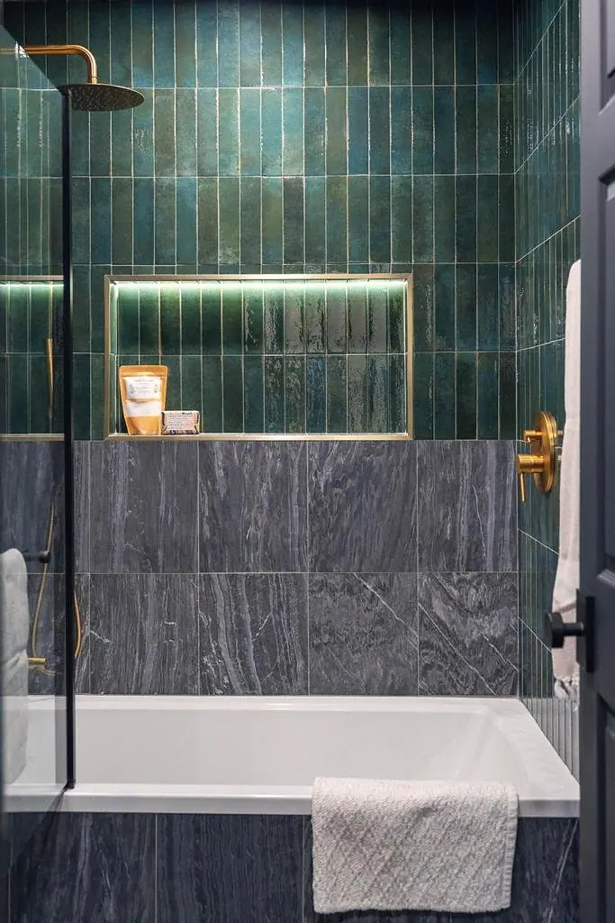 Crista da Montanha bath with emerald vertical tile, gray stone wainscot, and brass rain shower