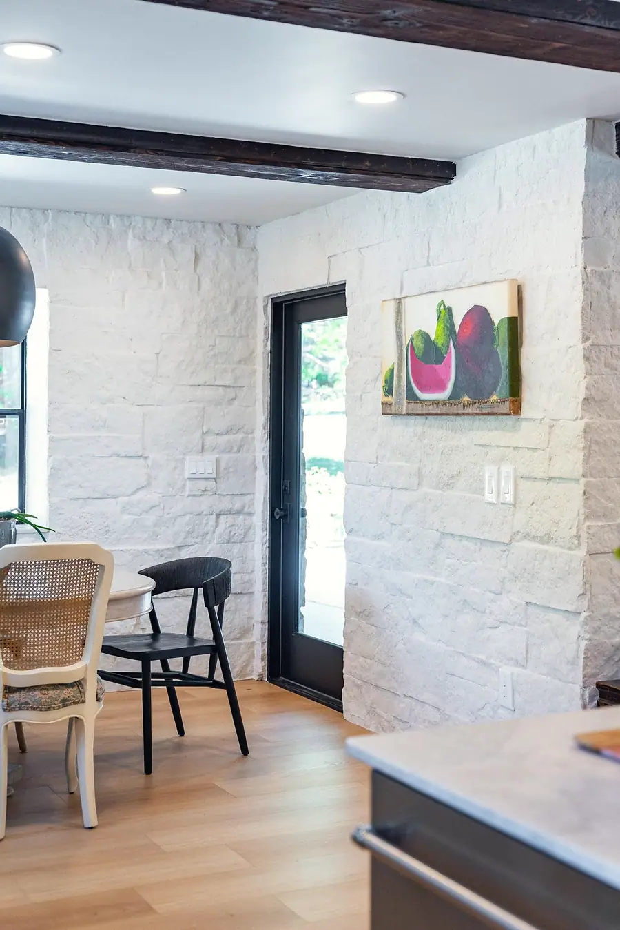 Little Gem dining corner with black French door and fruit still-life painting