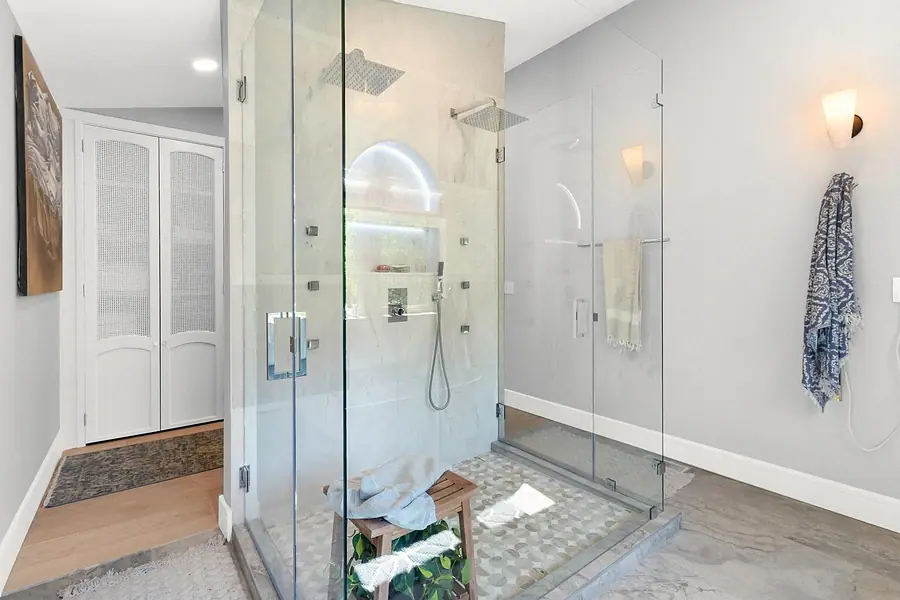 Elysium walk-in glass shower with dual rain heads and pebble floor
