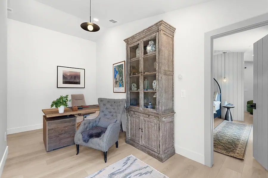 Little Gem office with wood desk, tufted gray chair, and weathered display cabinet