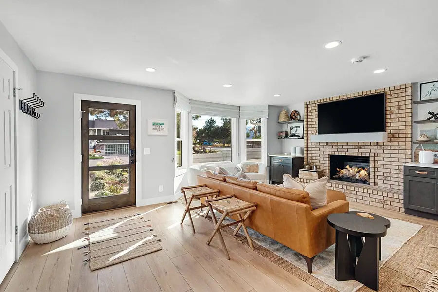 Midway living room from entry with leather sofa, brick fireplace, and bay windows