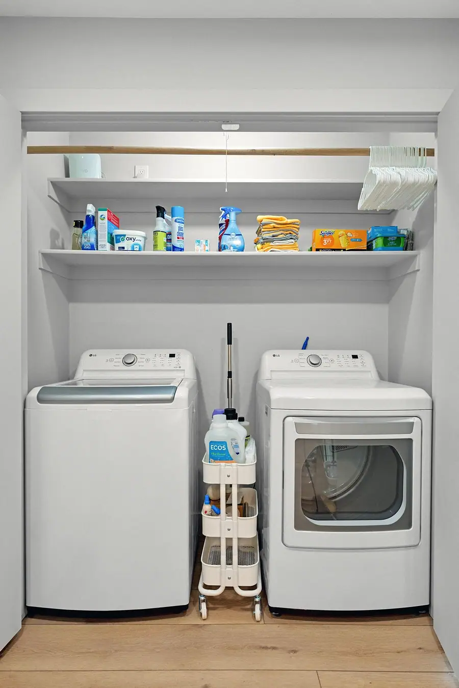 Midway laundry closet with side-by-side washer and dryer, open shelves, and rolling cart