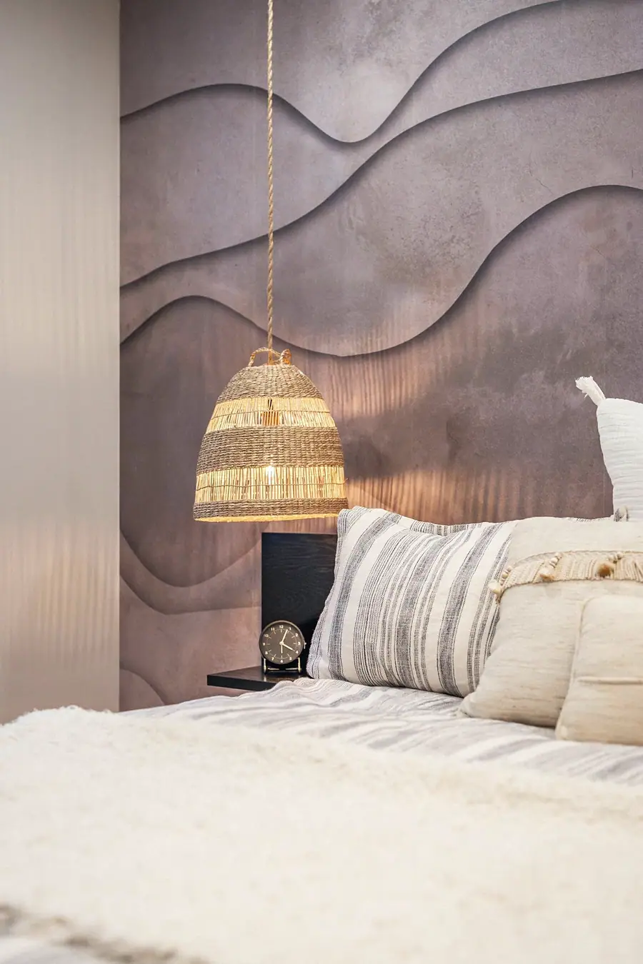 Grand Vista bedroom detail with woven pendant, striped pillows, and wave feature wall
