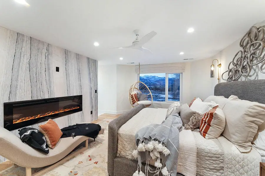 Primary suite with linear fireplace, chaise, and mountain window views