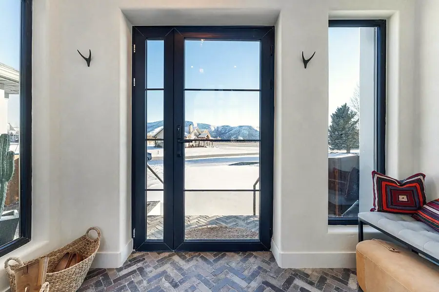 Foyer with black steel glass doors looking out to snowy mountain landscape