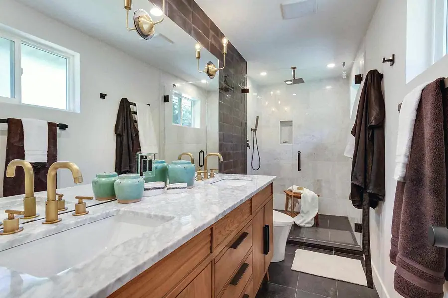 Wallace Project primary bathroom with dual vanity, brass fixtures, and walk-in shower