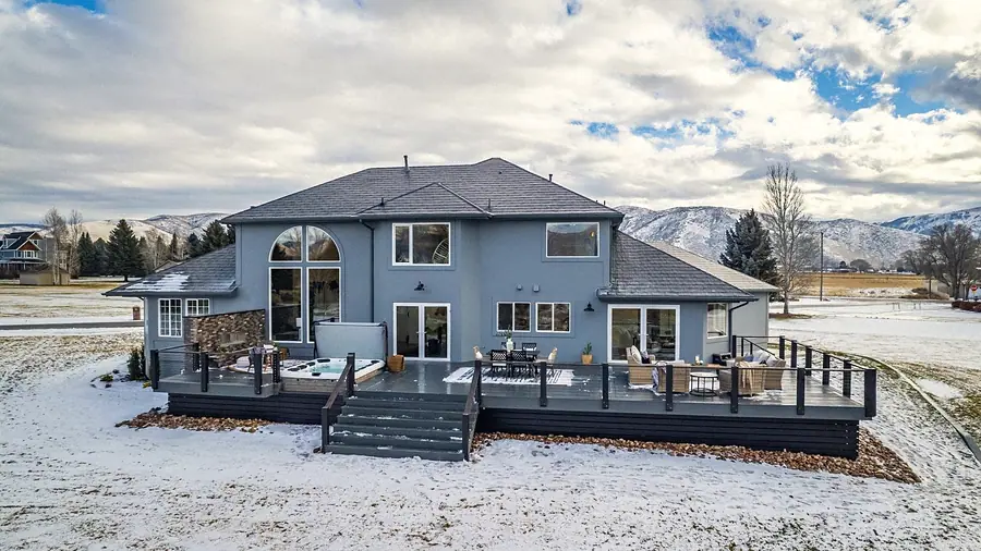 Rear deck with hot tub, outdoor dining, and lounge seating facing the mountains