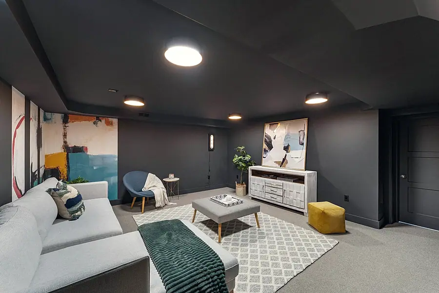 Fairway House basement lounge with charcoal walls, sectional sofa, and abstract art