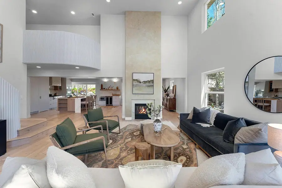 Grand Vista double-height living room with fireplace and open kitchen beyond