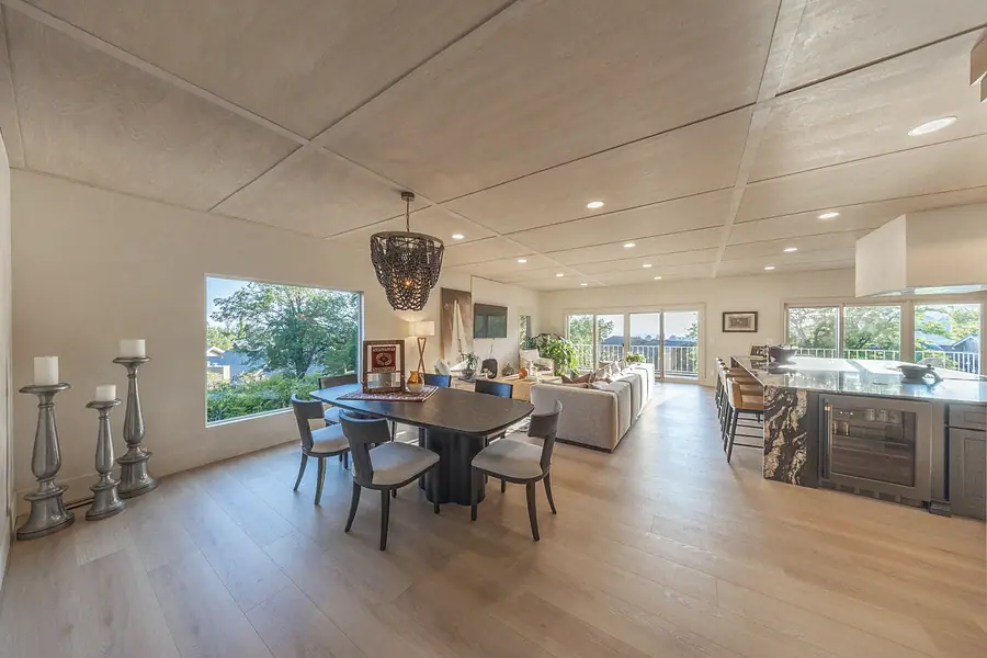 Open great room with wood ceiling, dining table, living area, and kitchen island framing mountain views
