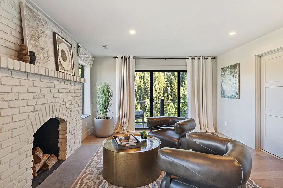 Matterhorn Hygge House living room with white brick fireplace, leather chairs, and forest patio doors