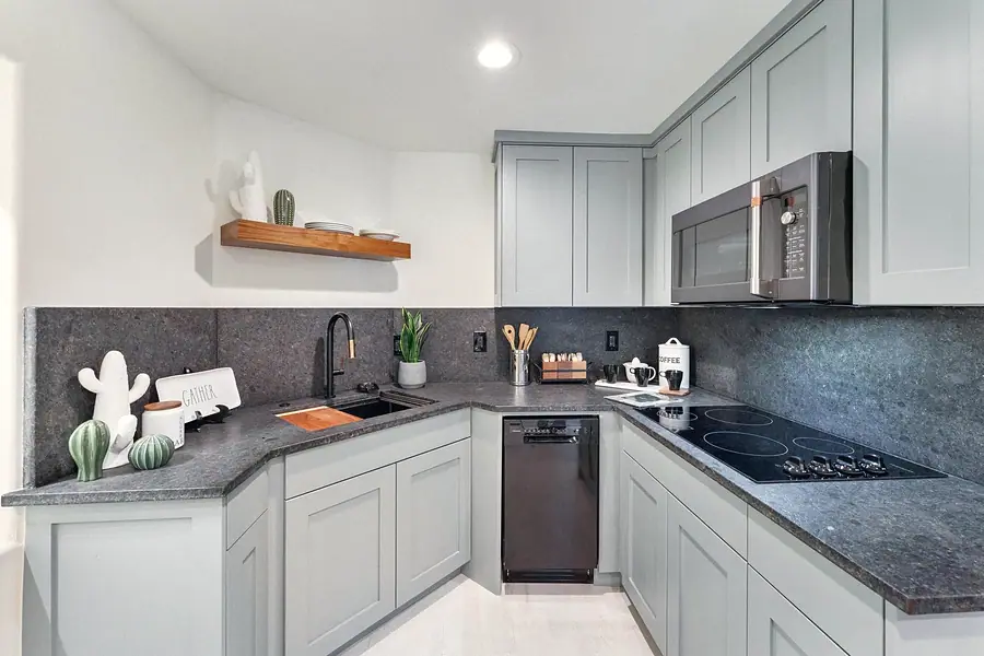 Lower kitchen corner with dark stone counters, cooktop, and open wood shelf
