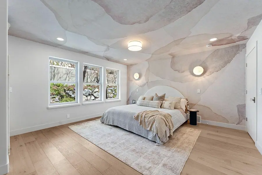 Grand Vista primary bedroom with watercolor mural ceiling, round headboard, and garden windows